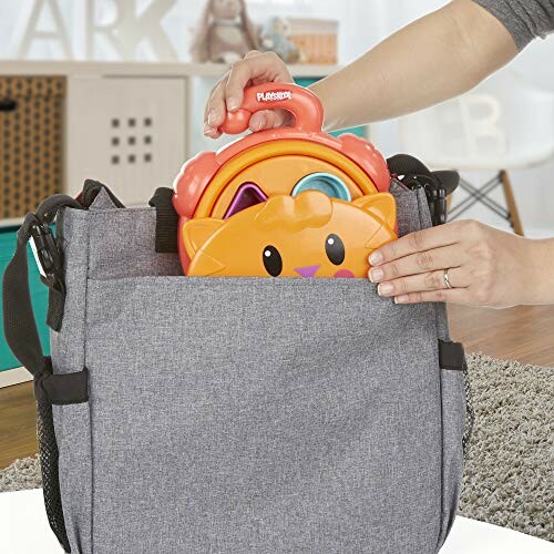 Person placing a cat-shaped toy in a gray bag.